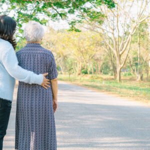 Señora mayor paseando de espaldas con una señora cuidadora acompañándola